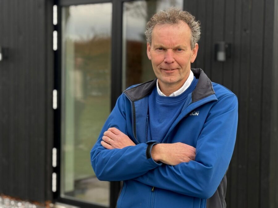 Mann steht vor moderner Fassade mit großen Glasflächen